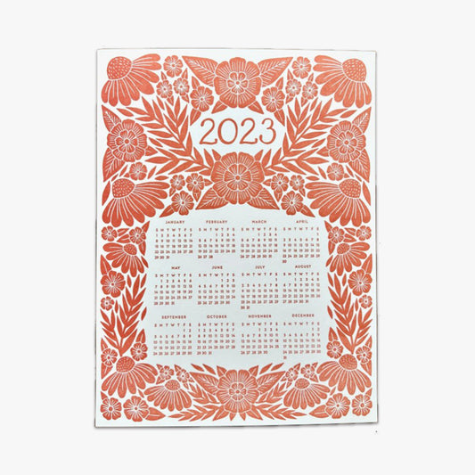 Our Red Floral Letterpress 2023 Calendar showcases a detailed floral graphic design that's letterpress printed with red ink on a thick museum, off-white board. The number 2023 is the headline on the upper third of the page, and the annual calendar (January through December,) is featured on the mid and lower third of the page. The 2023 calendar and 2023 headline are both surrounded by the floral graphic design. This photo shows the entire one-page calendar.